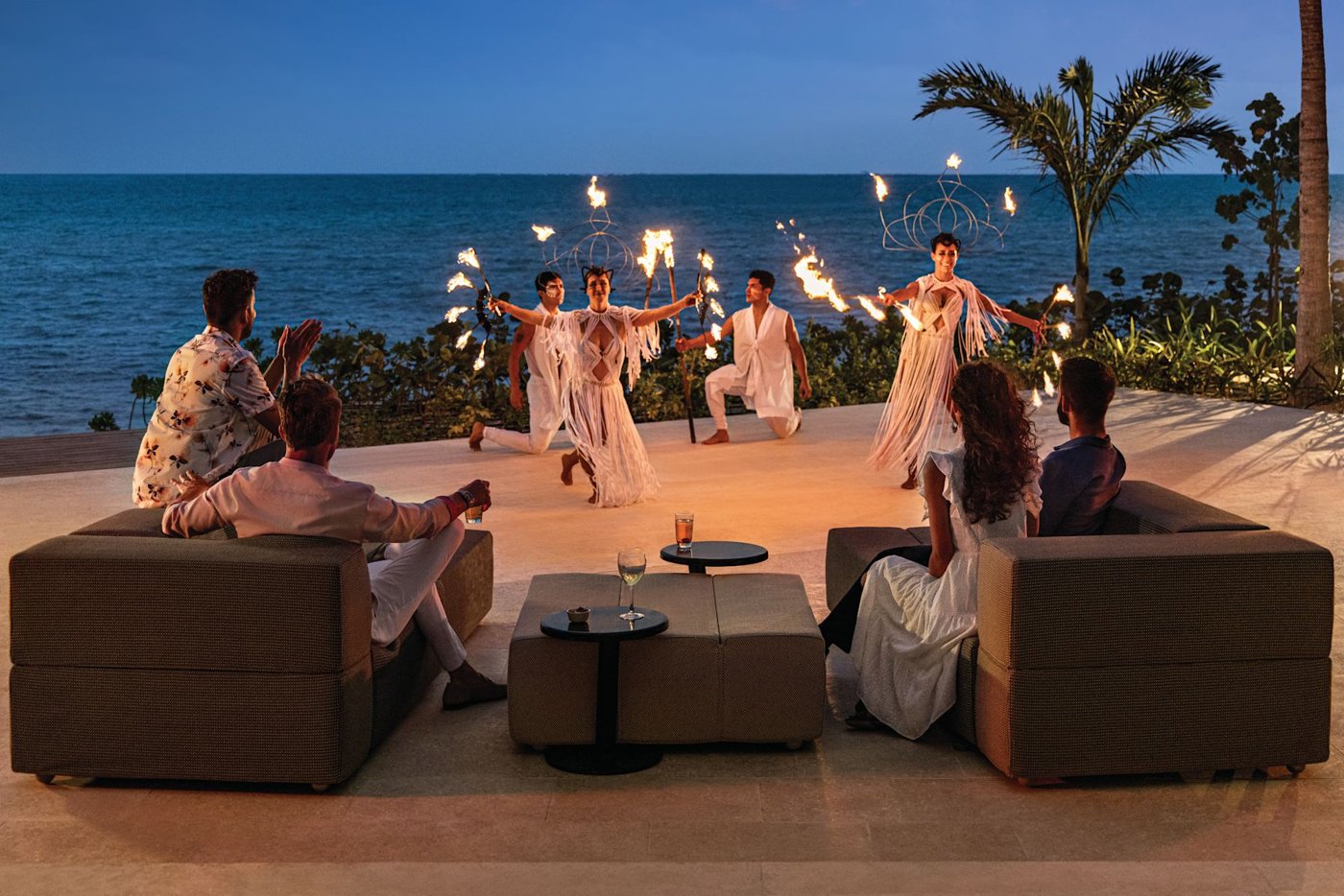 Guests watch a fire performance on an oceanfront terrace at Hilton Cancún