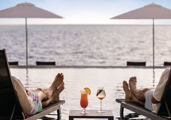 Guests relax beside an oceanfront pool at Hilton Cancún